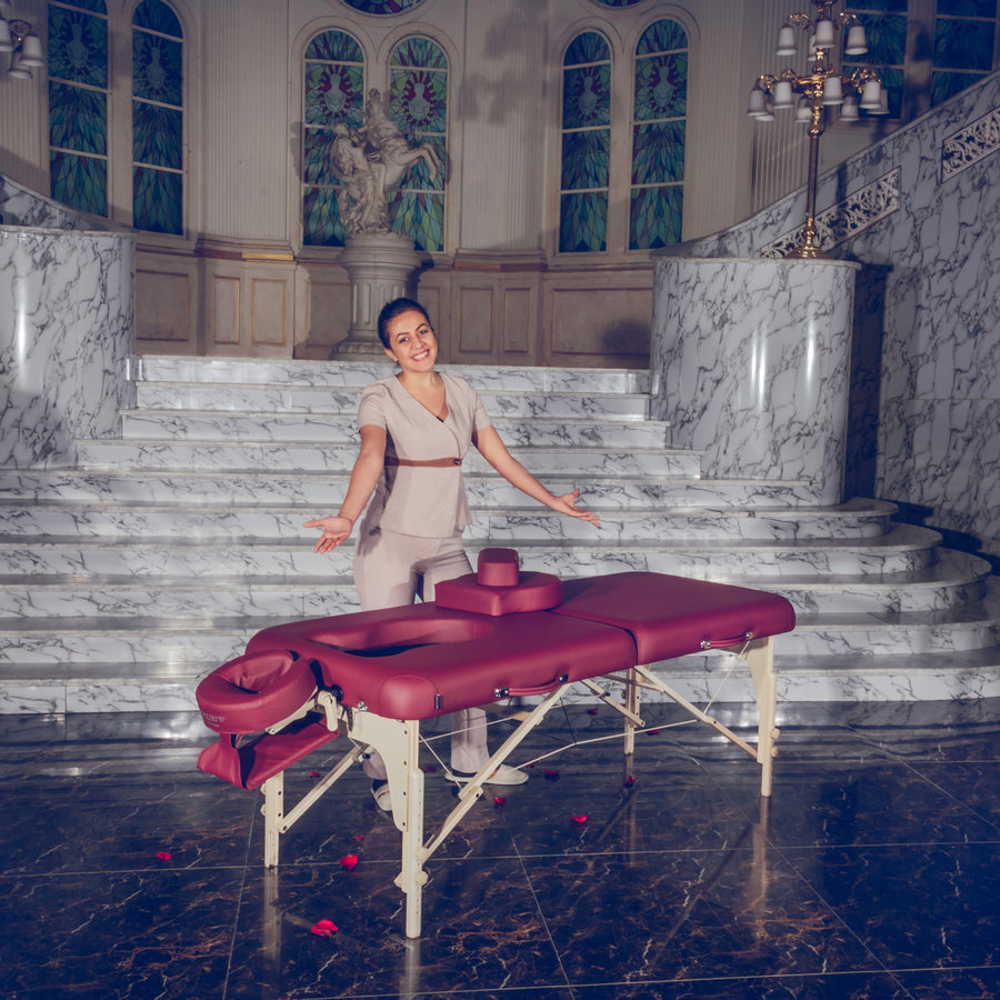 A woman stands behind a Master Massage EVA PREGNANCY Portable Massage Table in a grand room.