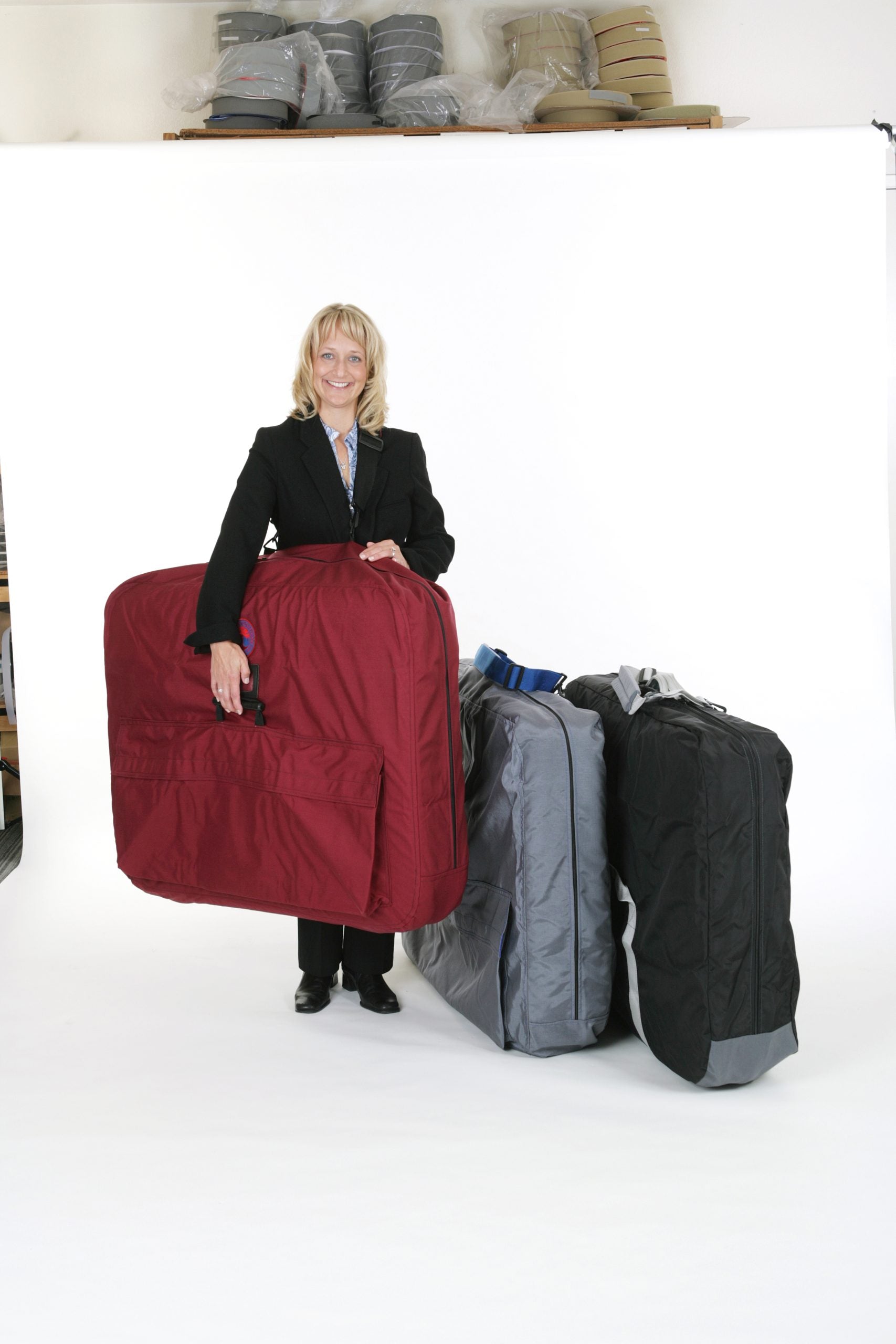 Woman with three travel bags for Pisces Pro NEW WAVE II Lite Portable Massage Table, on white.