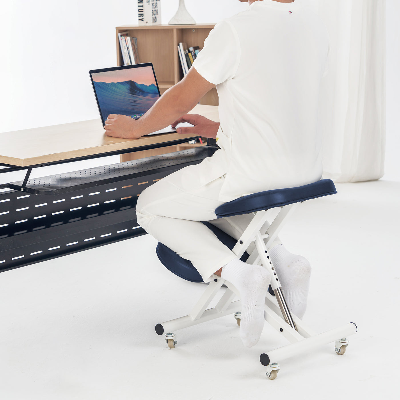 Person sitting on Master Massage Ergonomic Metal Foldable Posture Kneeling Chair at a desk with a laptop.