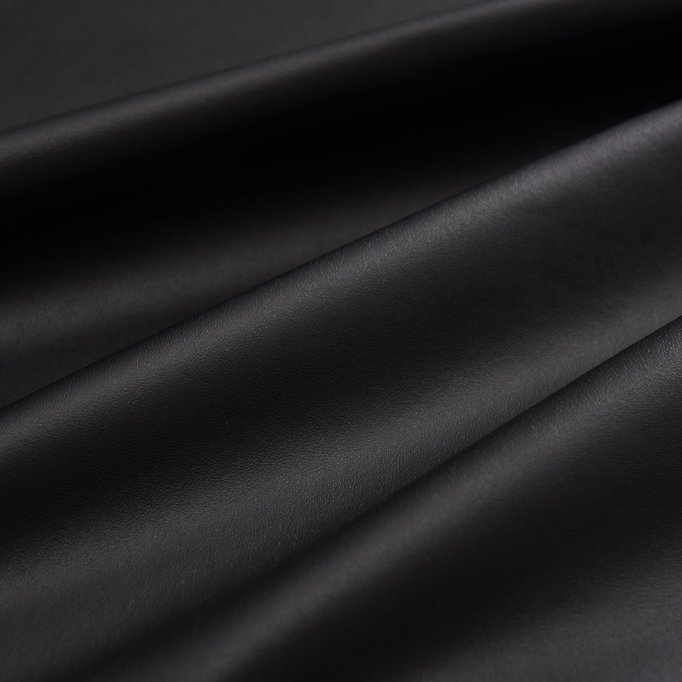 Close-up of black leather fabric with folds