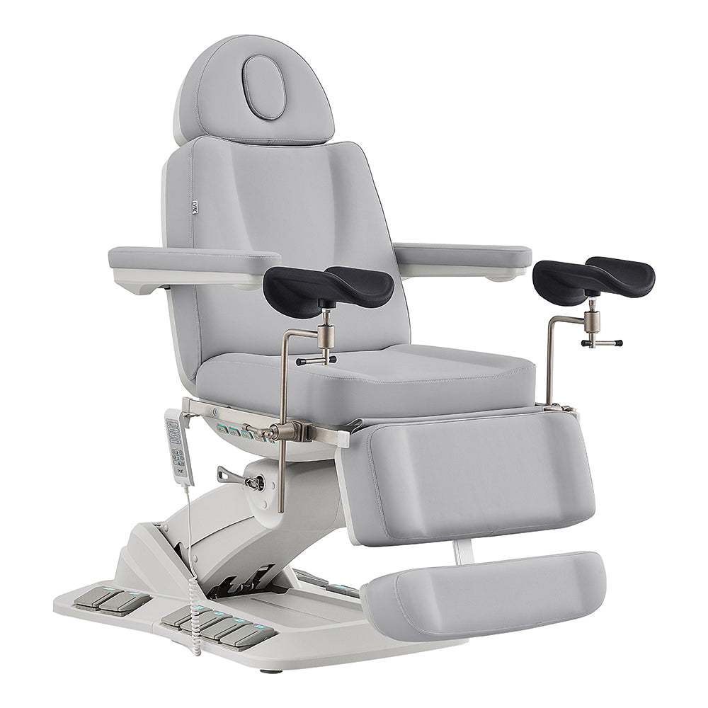 DIR Geneva Exam Table with stirrups, 4 motors, hand/foot remote, light gray upholstery.