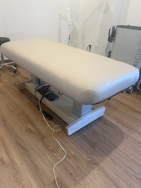 The Oakworks PERFORMALIFT Flat Top Electric Lift Table sits in a room with wood floors.