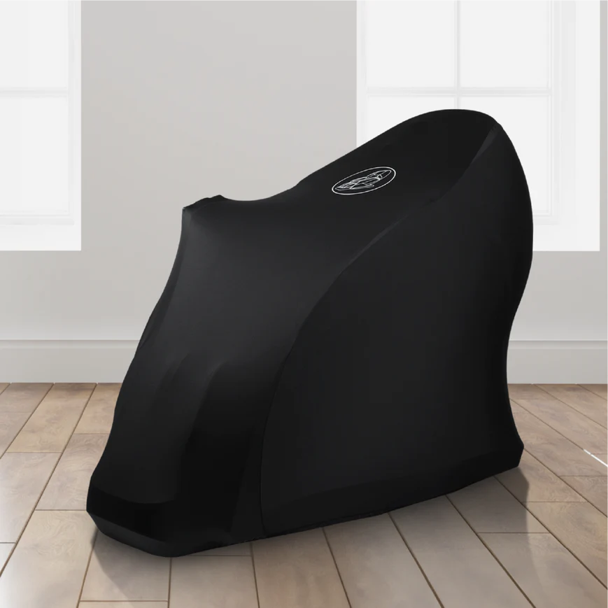 Black motorcycle cover beside a Titan Vending Massage Chair on wooden floors, white walls.