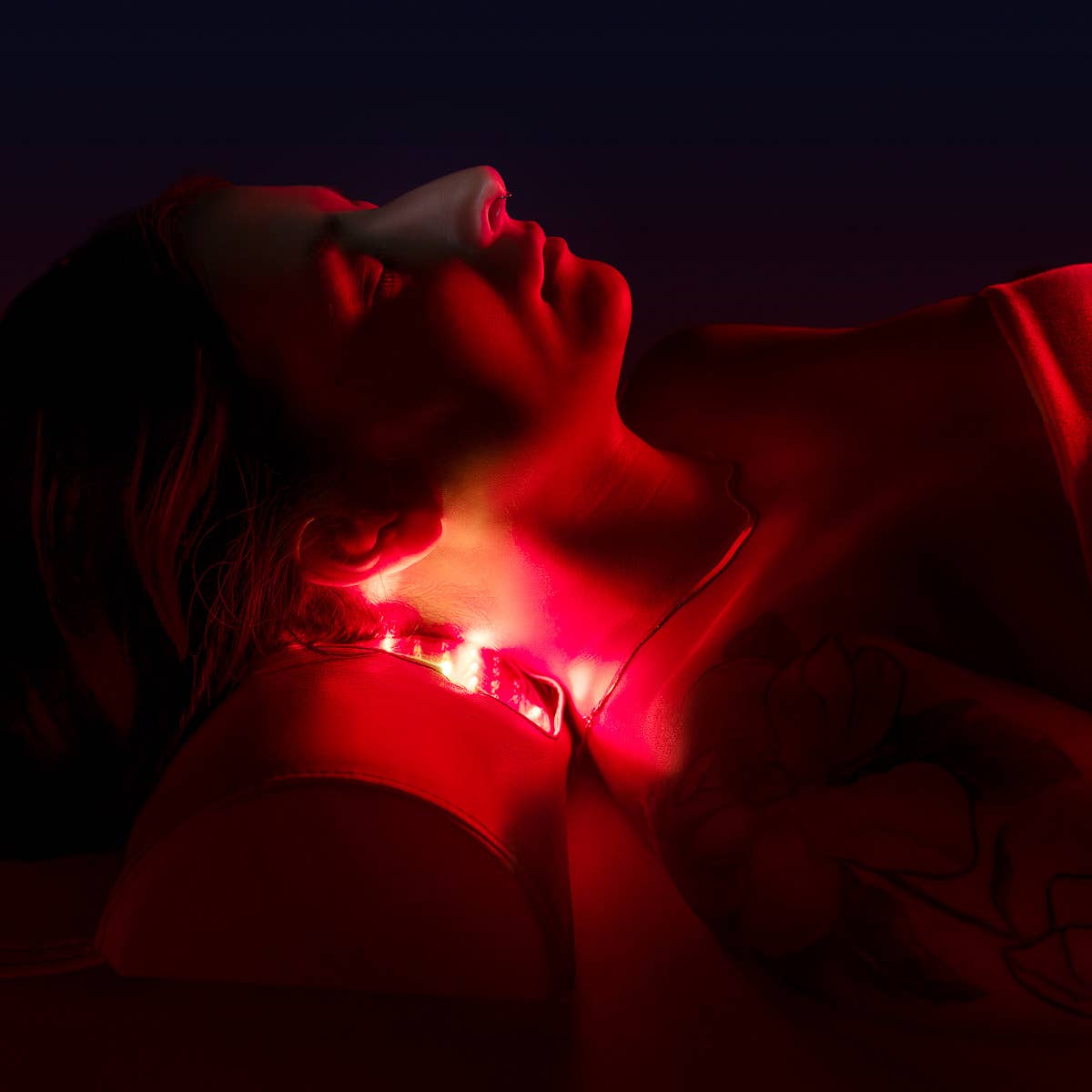 Person on Living Earth Crafts RADIANCE PT LED Therapy Table in a dark room, light on neck.