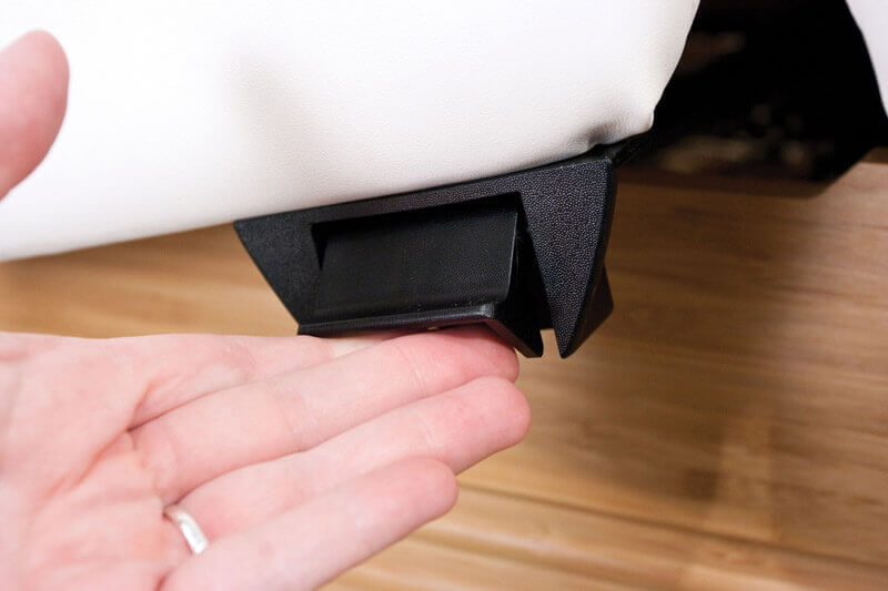 A hand presses a black latch under the Oakworks CLINICIAN Adjustable Lift-assist Salon Top.