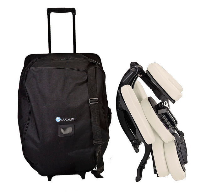 EarthLite AVILA II massage chair with cream padding next to a black rolling travel bag.
