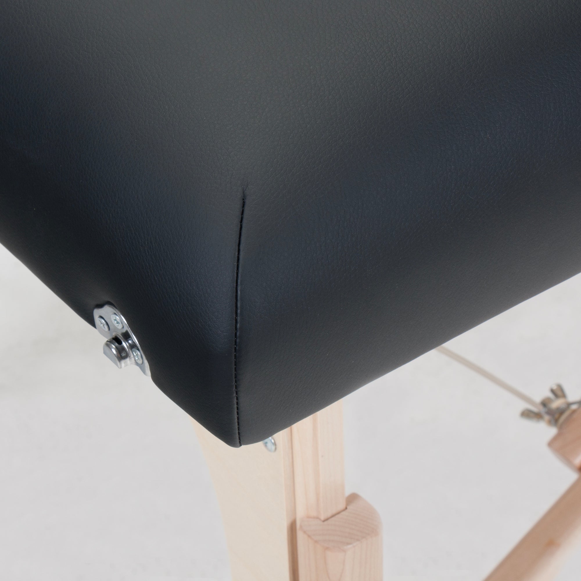 Close-up of Stronglite CLASSIC DELUXE Table’s black cushioned seat and wooden legs.
