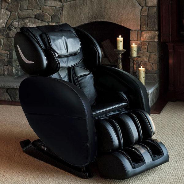Infinity Smart X3 3D/4D Massage Chair by Infinity in a cozy room with fireplace and lit candles.