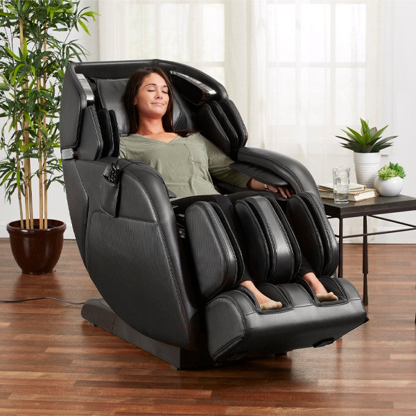 Woman relaxing in a Kyota M673 Kenko 3D/4D Massage Chair (Certified Preowned) in a bright room.