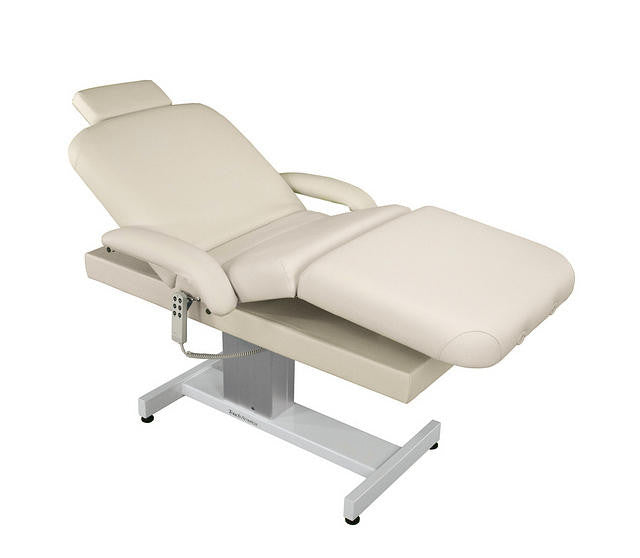 TouchAmerica VENETIAN POWERTILT beige treatment table with padded armrests and metal base.