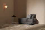 Gray Ceragem S4 Massage Lounger in a minimalistic room with a side table and wall light.