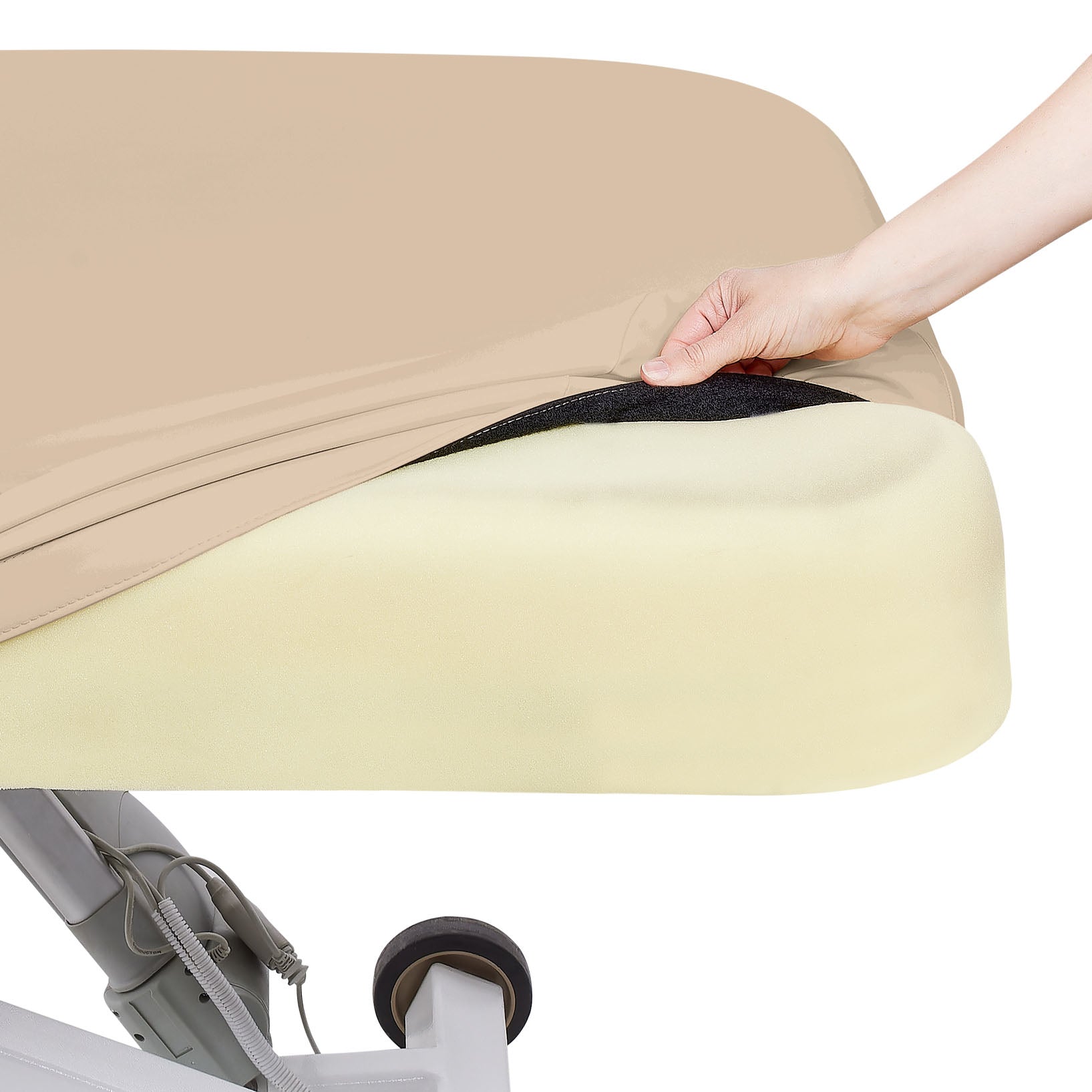 A hand lifts a beige cover on an EarthLite ELLORA LX FLAT treatment table’s foam mattress.