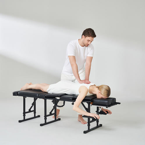 Person receiving a massage on a black massage table with a white background