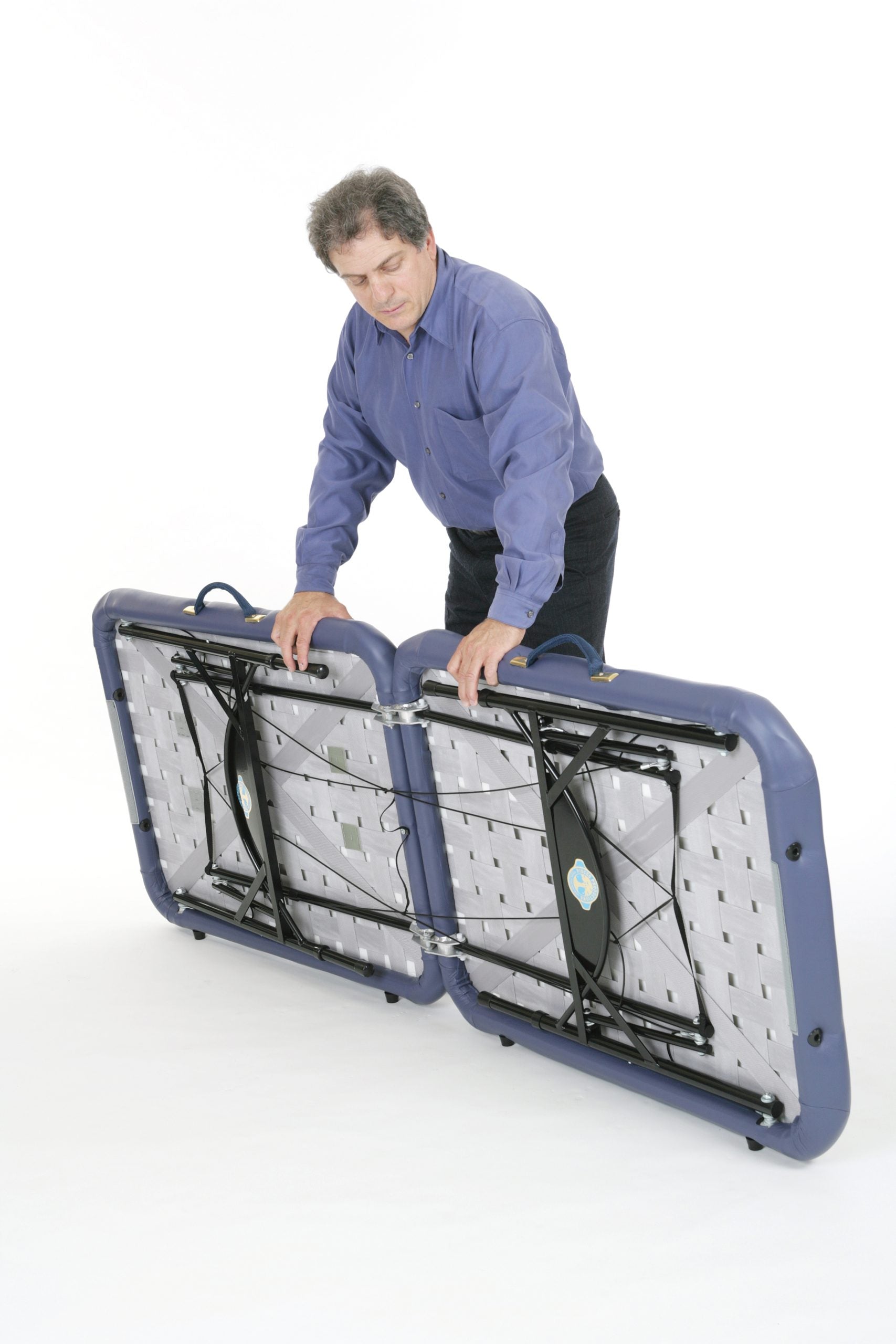 Man folding a Pisces Pro NEW WAVE II Lite Portable Massage Table against a white background.