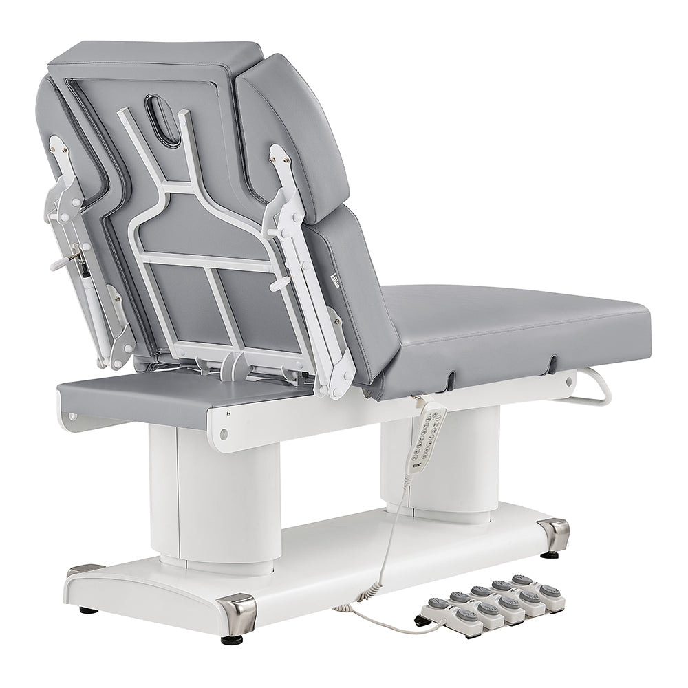 Medical examination table with adjustable headrest and foot controls on a white background