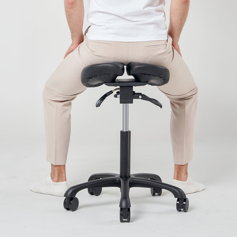Person sitting on a black adjustable stool with a white background
