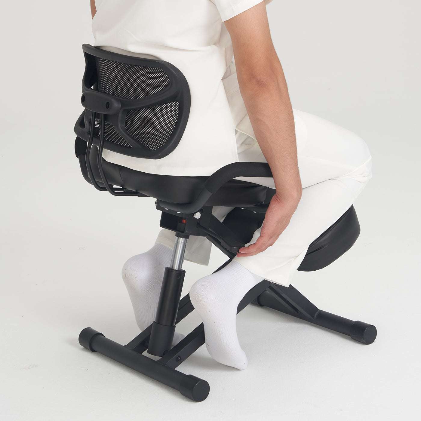 Person in white using Master Massage Ergonomic Kneeling Chair with mesh back and footrest.
