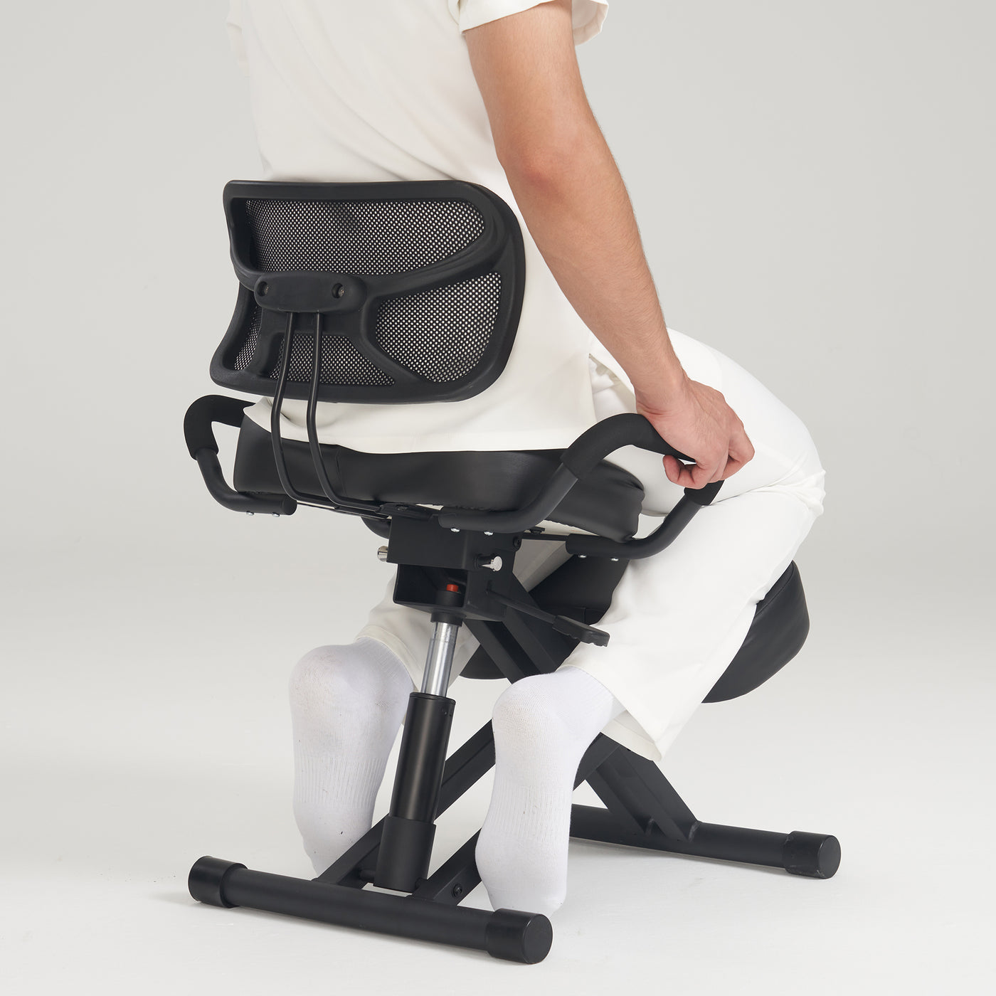 Person sitting on a Master Massage Ergonomic Kneeling Chair with back support, viewed from behind.