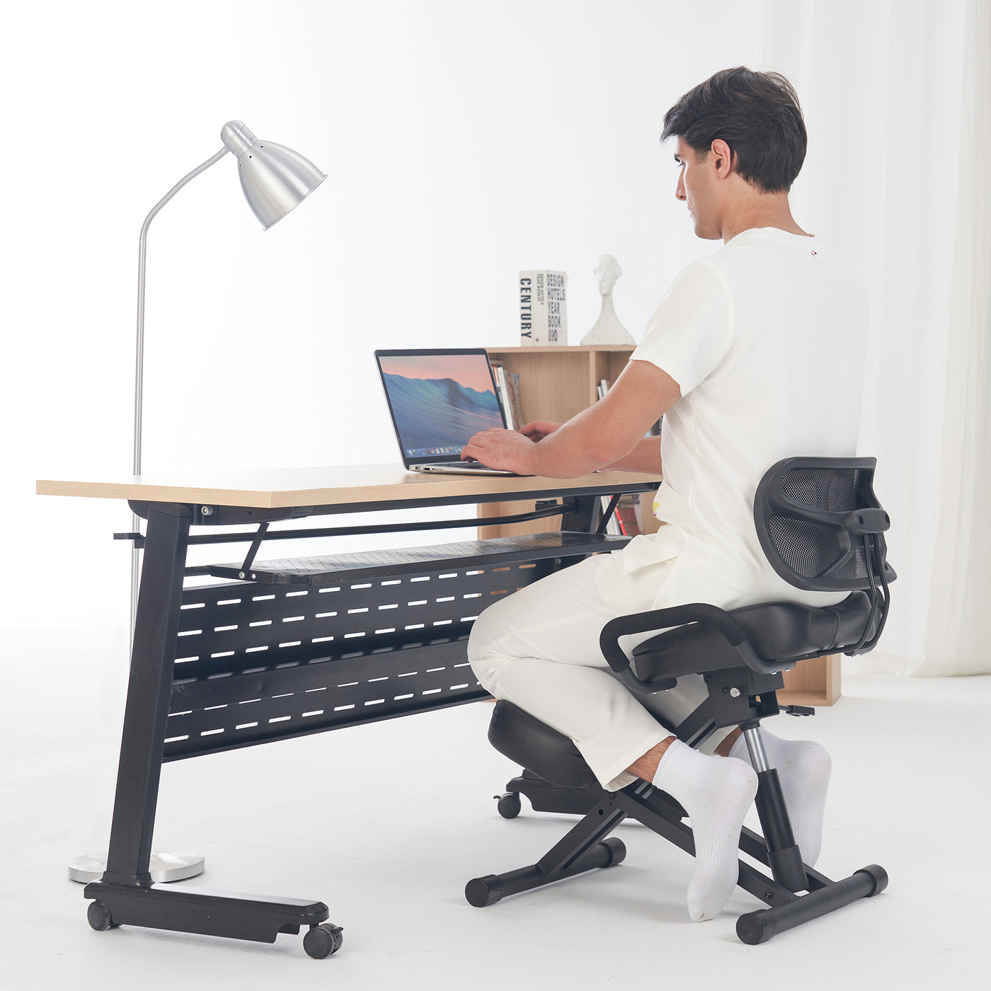 Person using a laptop while seated on a Master Massage Ergonomic Kneeling Chair with Back Support.
