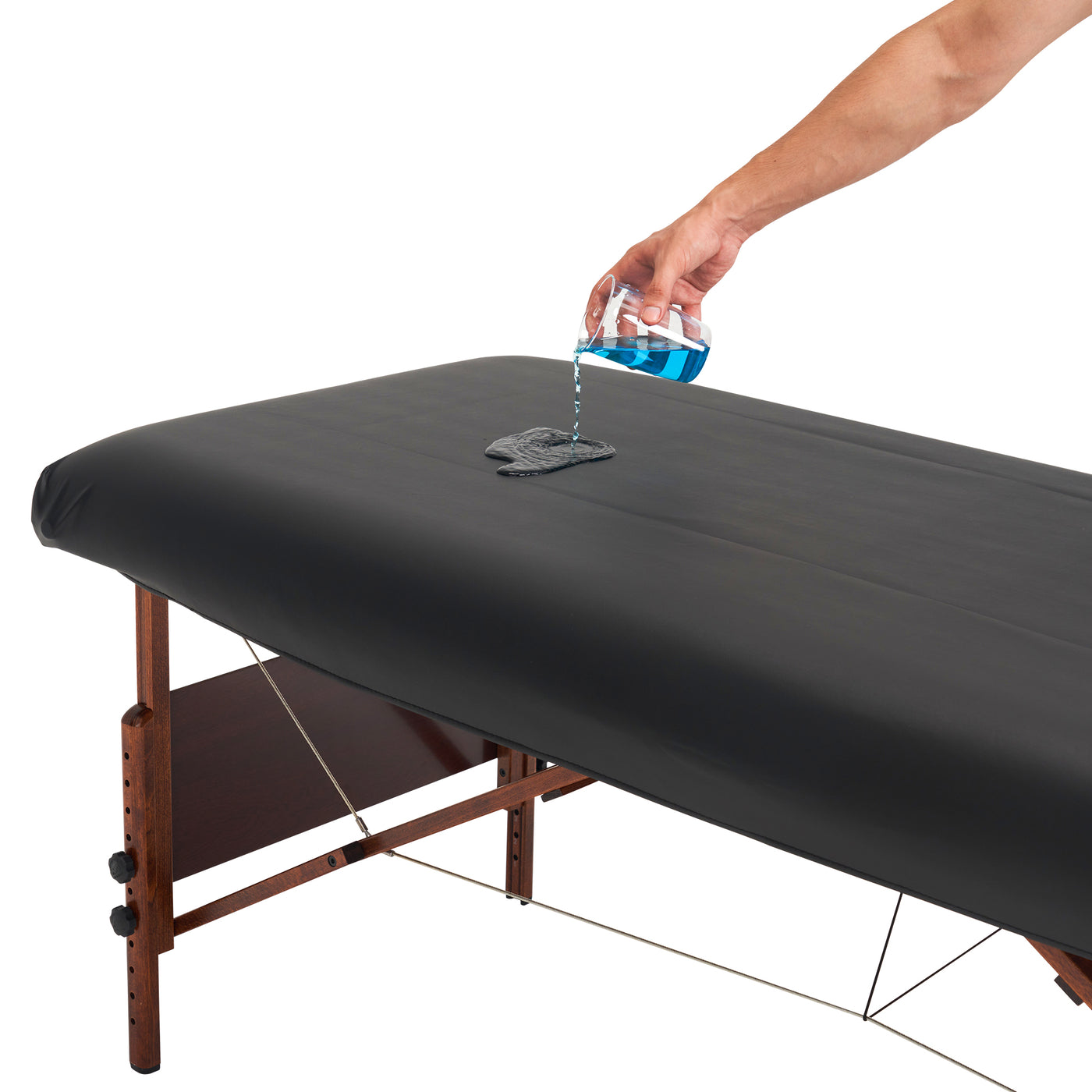 Person pouring a blue liquid onto a black cover with a white background