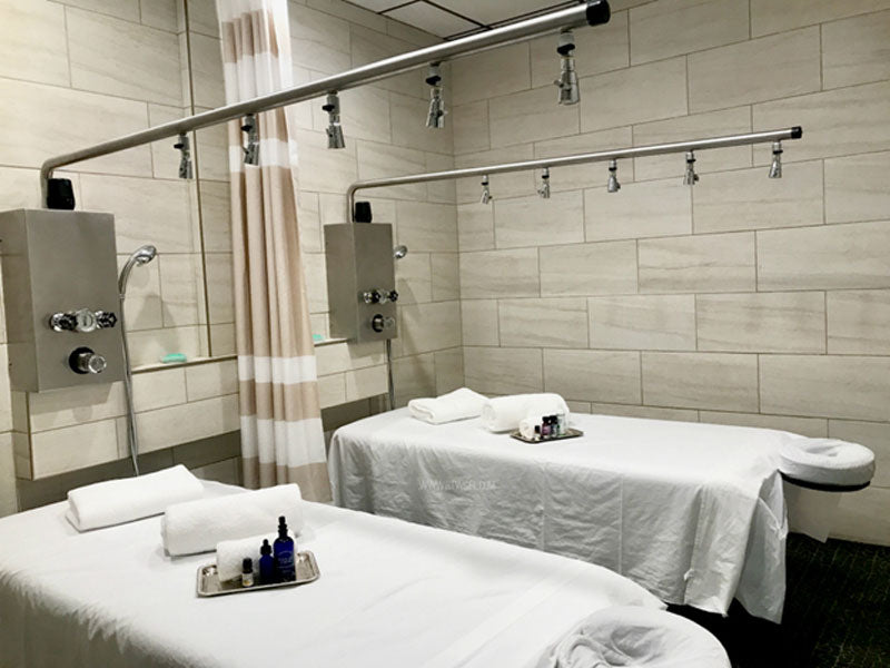Two wet tables feature Water Werks Cascade 5 Head Vichy Showers and plush towels in a spa room.