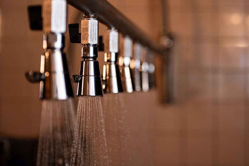 Close-up of a shower head with water flowing, blurred background