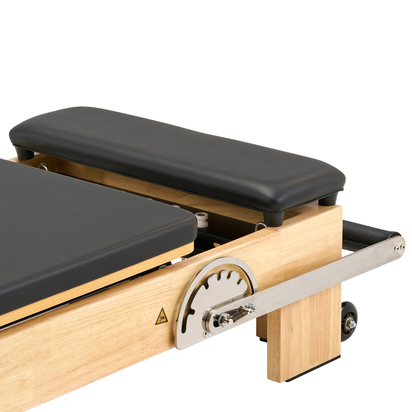 Close-up of a Pilates reformer machine showing the black padded carriage, light wood frame, metal adjustment dial, and wheels on a white background.