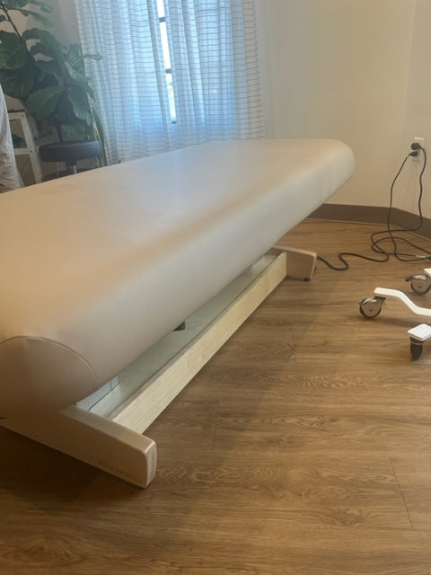 The Oakworks PERFORMALIFT Flat Top Electric Lift Table in a room with wood floors and equipment.