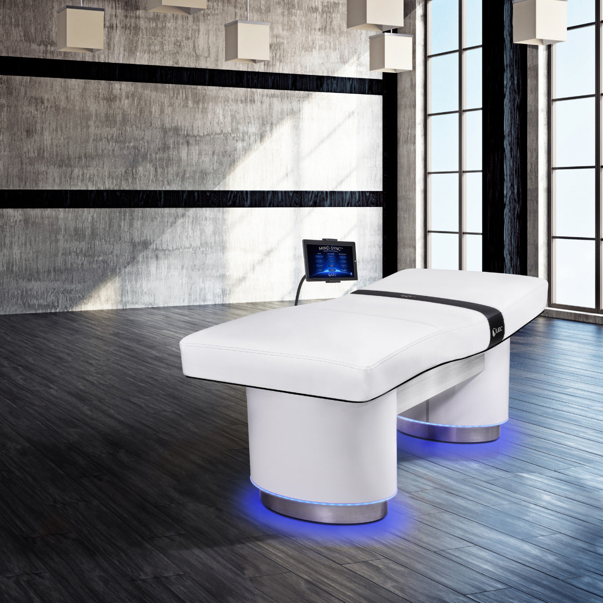 Modern room with a Living Earth Crafts INSIGNIA 2.0 ELLIPSE™ Multi-Purpose Treatment Table and Mind-Sync™ Restorative Vibrational Wellness device on a wooden floor.