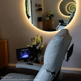 The Living Earth Crafts Mind-Sync 2.0™ Lounger faces a round, backlit mirror in a sleek room.