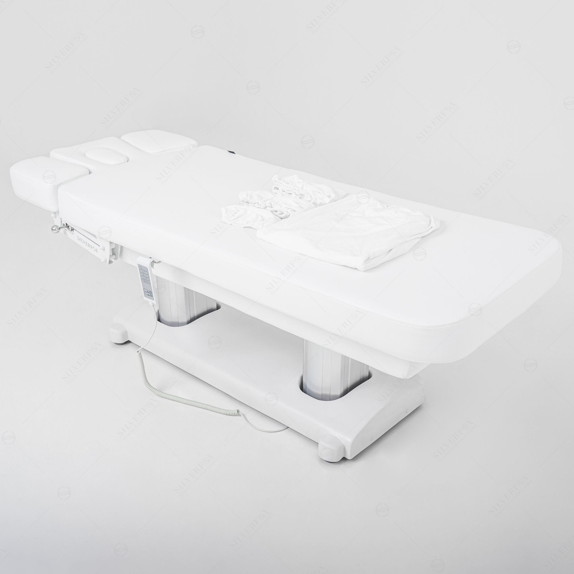 The Silverfox America OCILI 2249, a white 4-motor table, sits with linens and pillows in a minimal space.