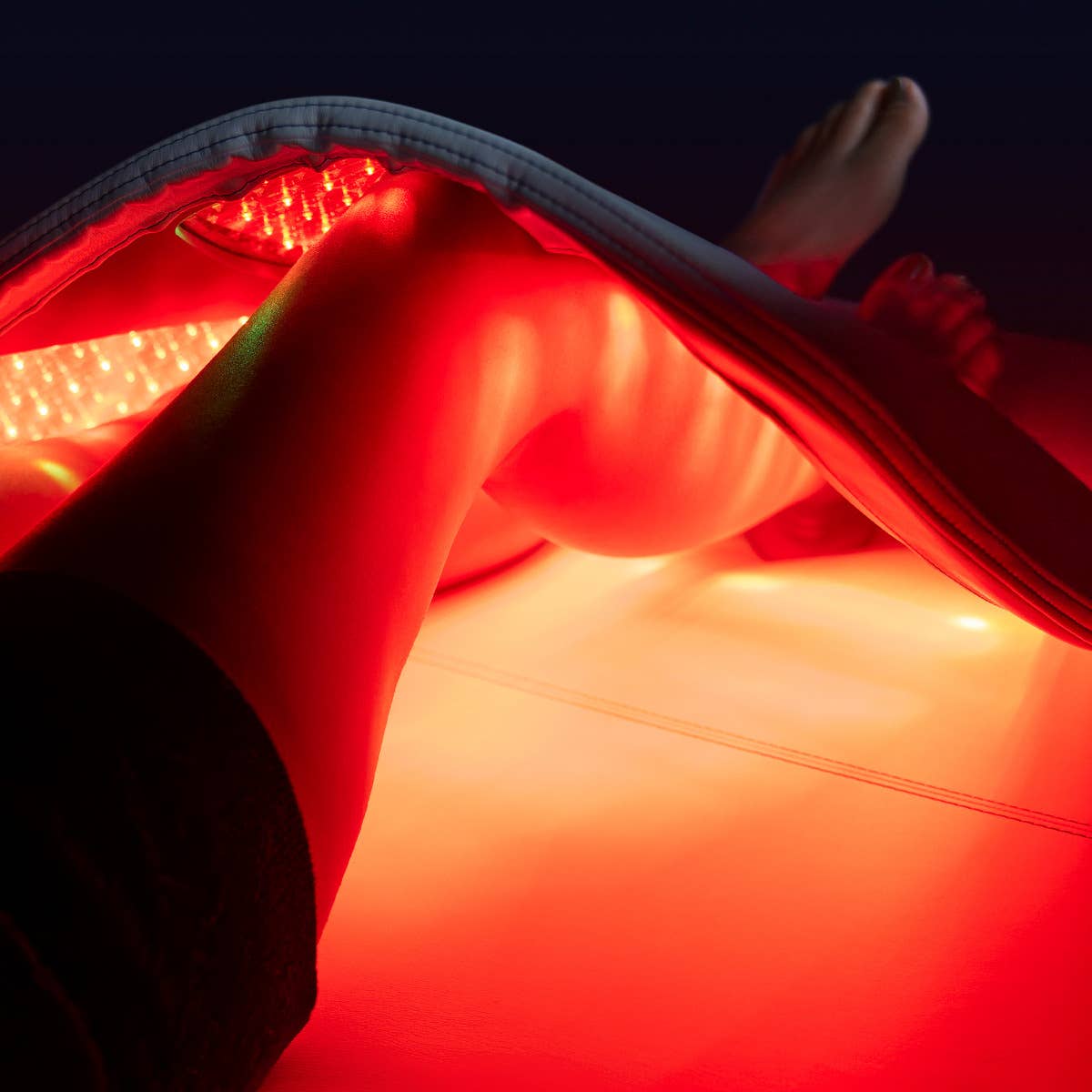 Person uses Living Earth Crafts RADIANCE PT LED Therapy Table for pain management on legs.