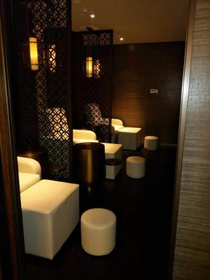 Dimly lit lounge with TouchAmerica DESTINY Pedicure Chairs, round stools, and partition walls.