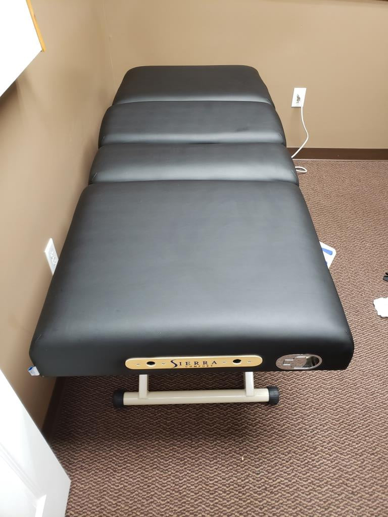 Sierra Comfort Adjustable 4-Section Electric Lift Table in a small room with brown carpet.