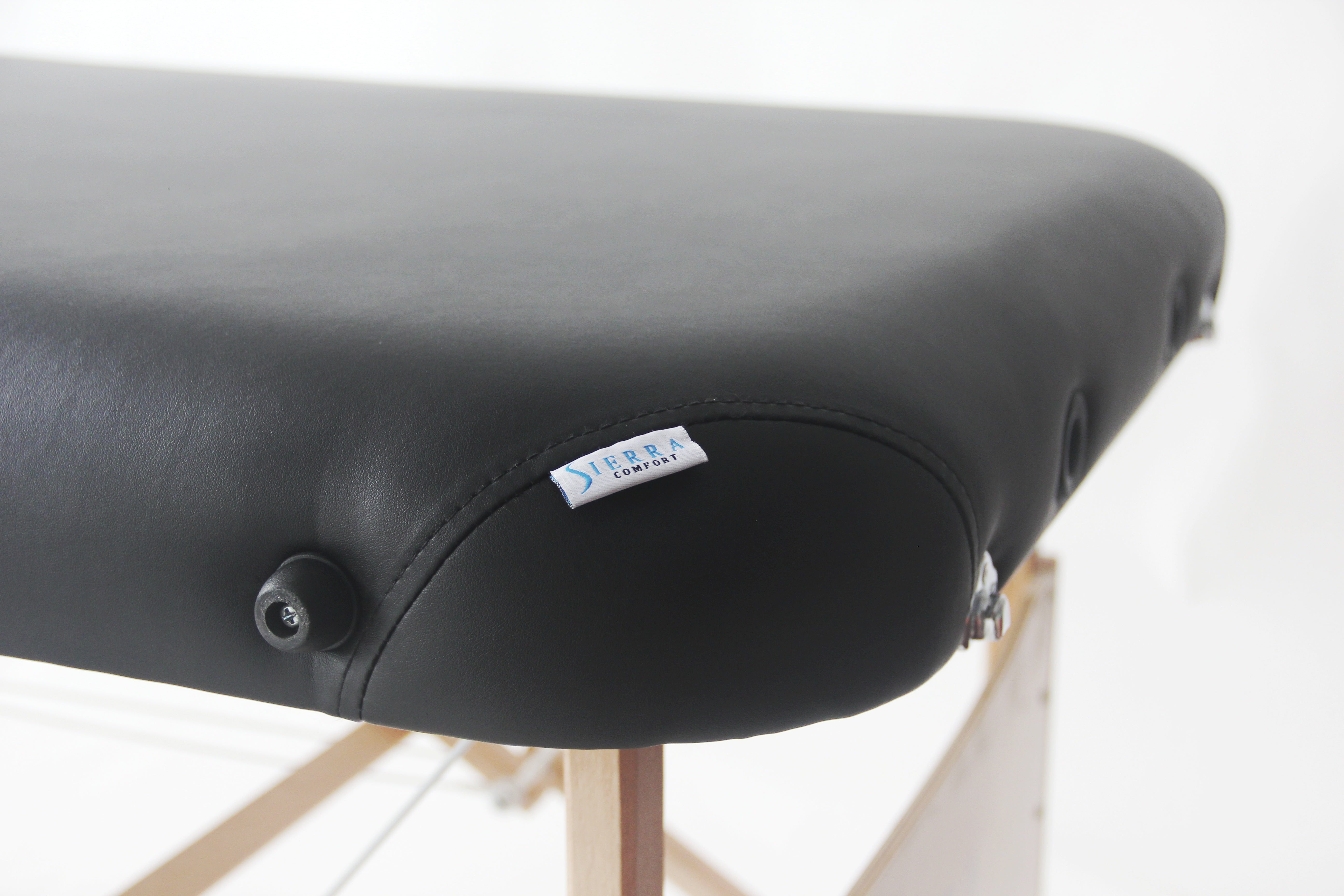 Sierra Comfort ALL-INCLUSIVE portable massage table with wooden legs and visible brand tag.