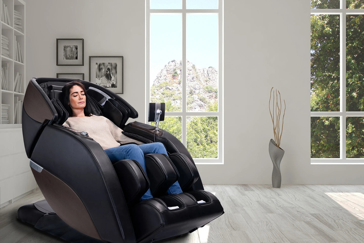 Woman relaxes in a Kyota Nokori M980 Syner-D massage chair with mountain views through windows.
