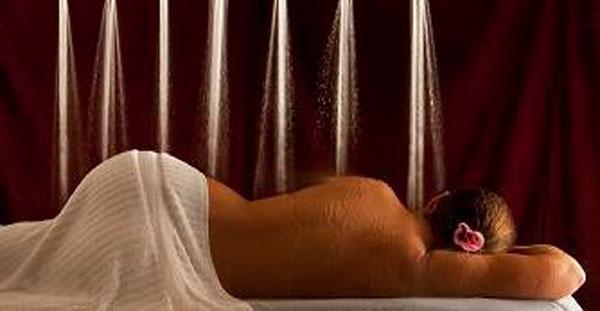 Person lies face down as Water Werks Torrent Vichy Shower streams water for hydrotherapy session.