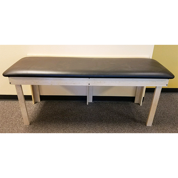 PHS Medical Wall Mount Folding Treatment Table with wooden legs and high-density foam cushion.