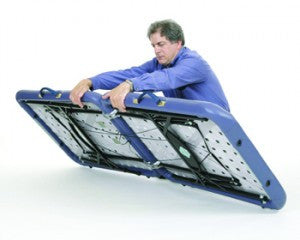 Man folding a Pisces Pro NEW WAVE II Lite Portable Massage Table against a white background.