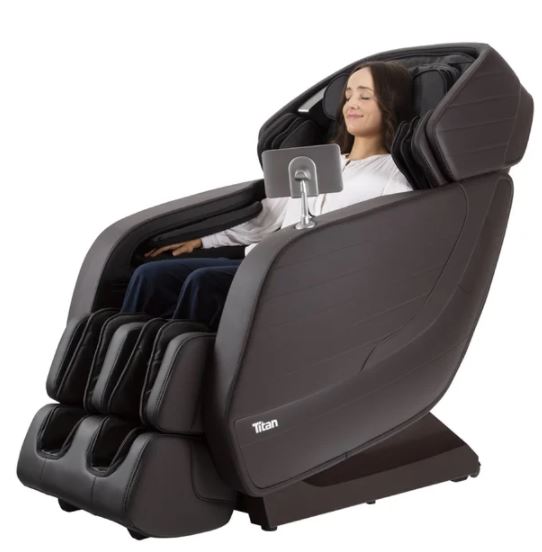 Woman relaxing in a Titan JUPITER LE massage chair, eyes closed, using the mounted tablet.