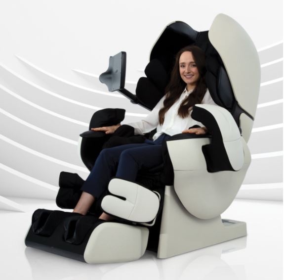 A woman relaxes in an Osaki INADA AI ROBO Electric Massage Chair with a screen attached.