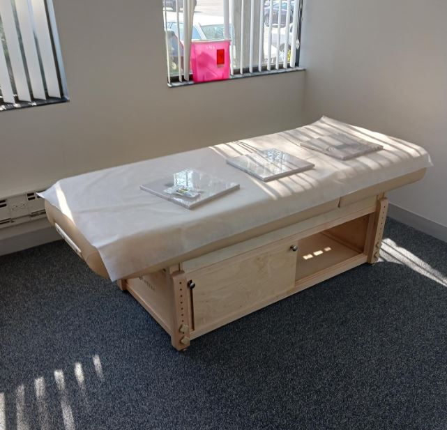 EarthLite SEDONA TILT table with paper cover, three folders on top, in a sunlit carpeted room.